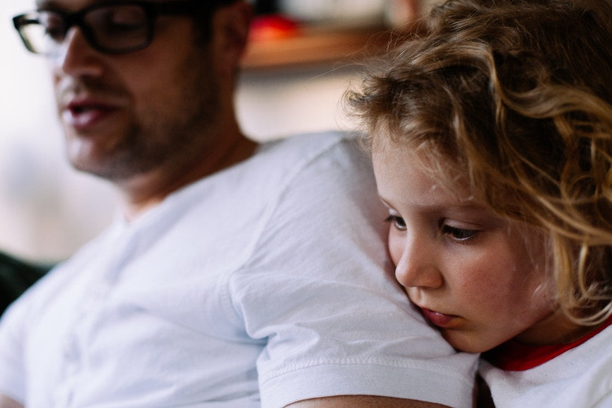dad with a white shirt reading to a child who is looking