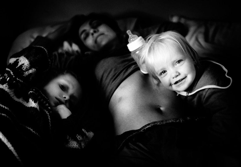 child lying on top of mother holding feeding bottle