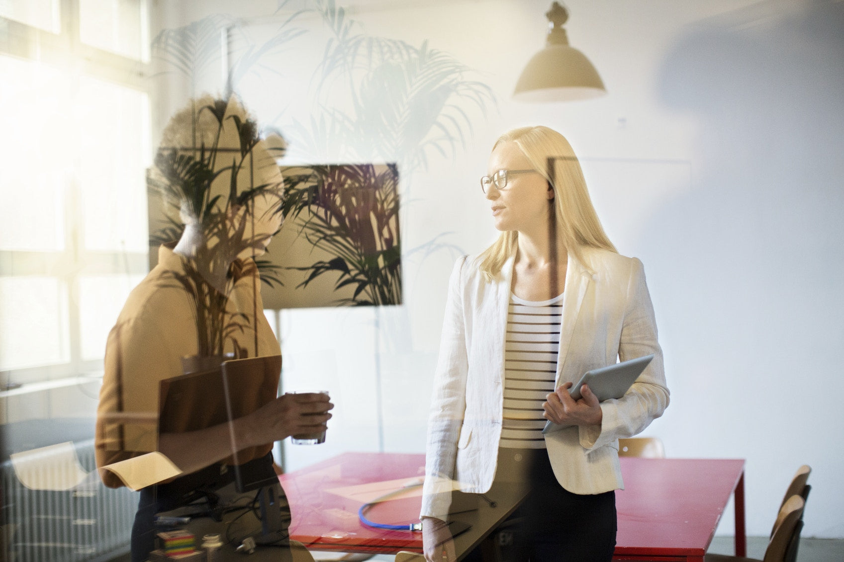 Two women stand in the office near the table