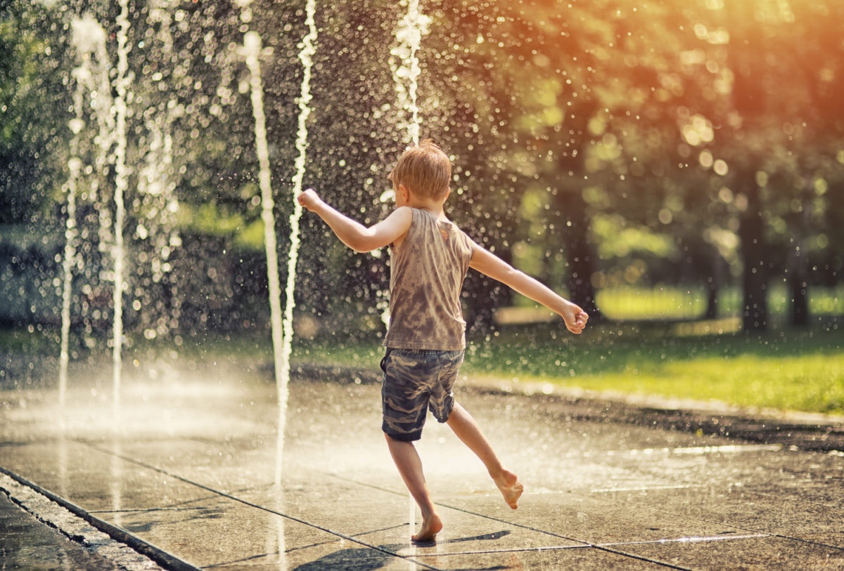boy playing with water from a fountain