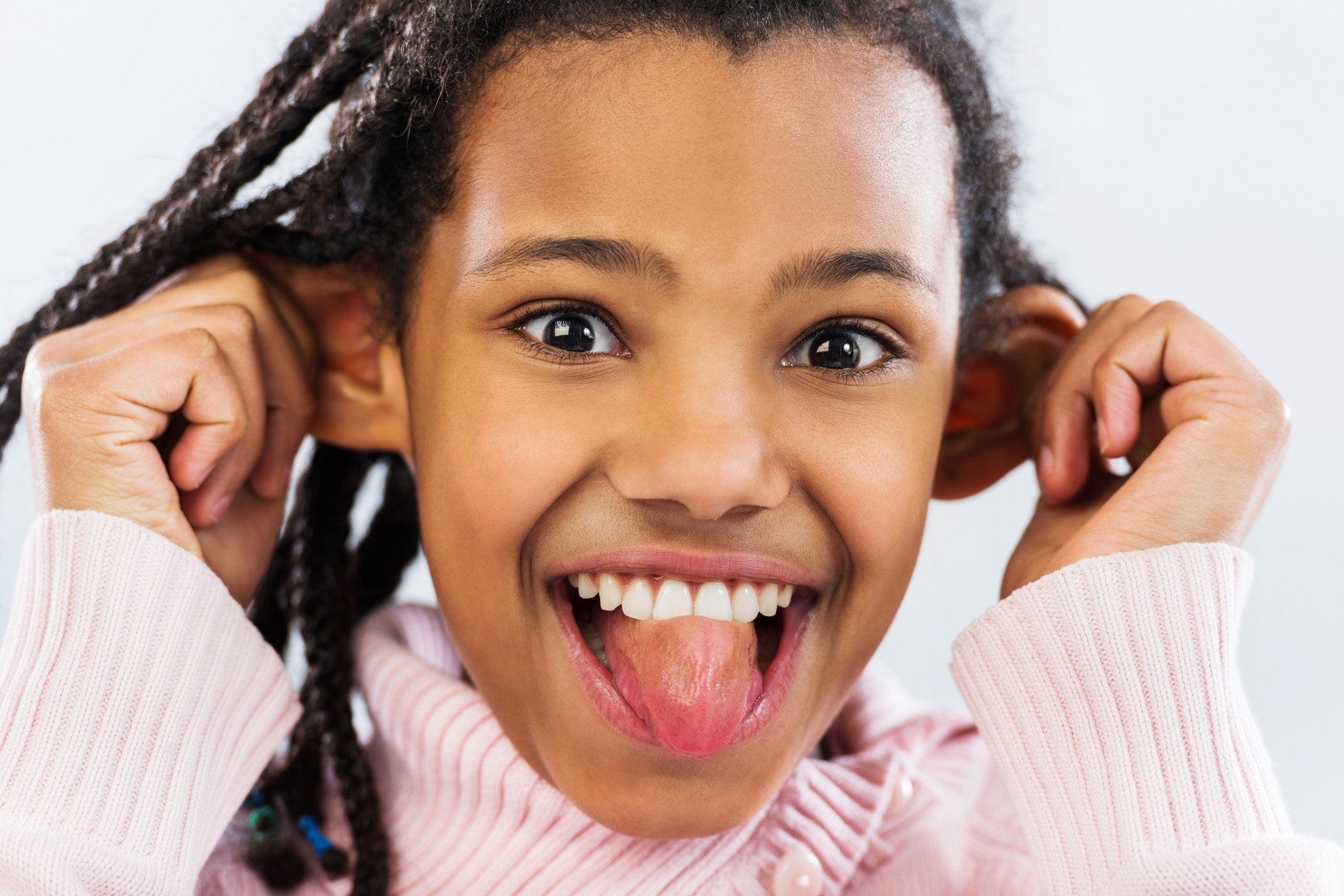 young girl sticking out her tongue and pulling her ears