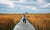 young boy running with a backpack on long flat trail made of wood