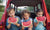 two young Girls and a boy eating watermelon on back of car