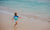 Little boy running and jumping at sea shore.