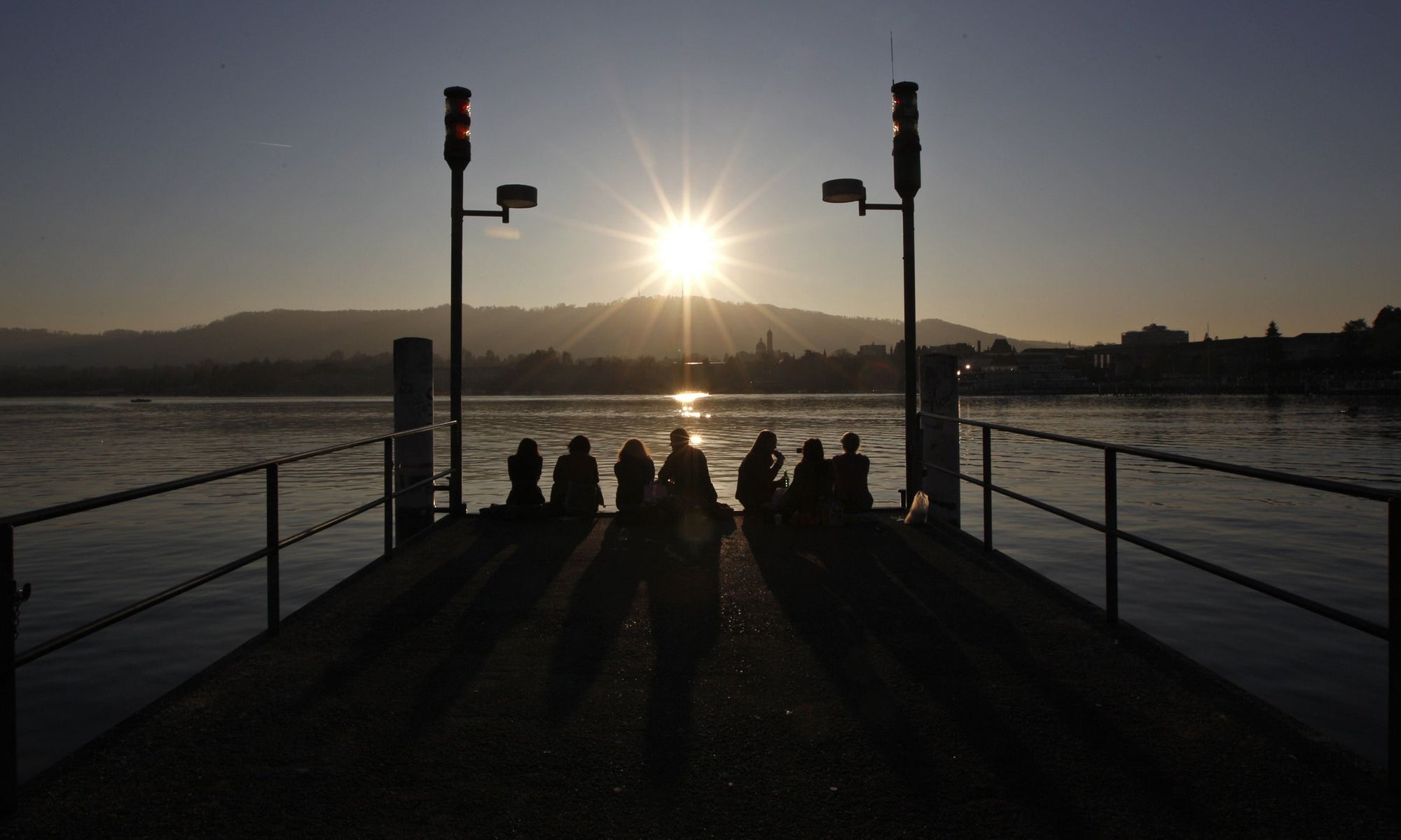 friends sitting on wooden dock during sunset