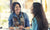 two women sitting at table and drinking cofee and smiling