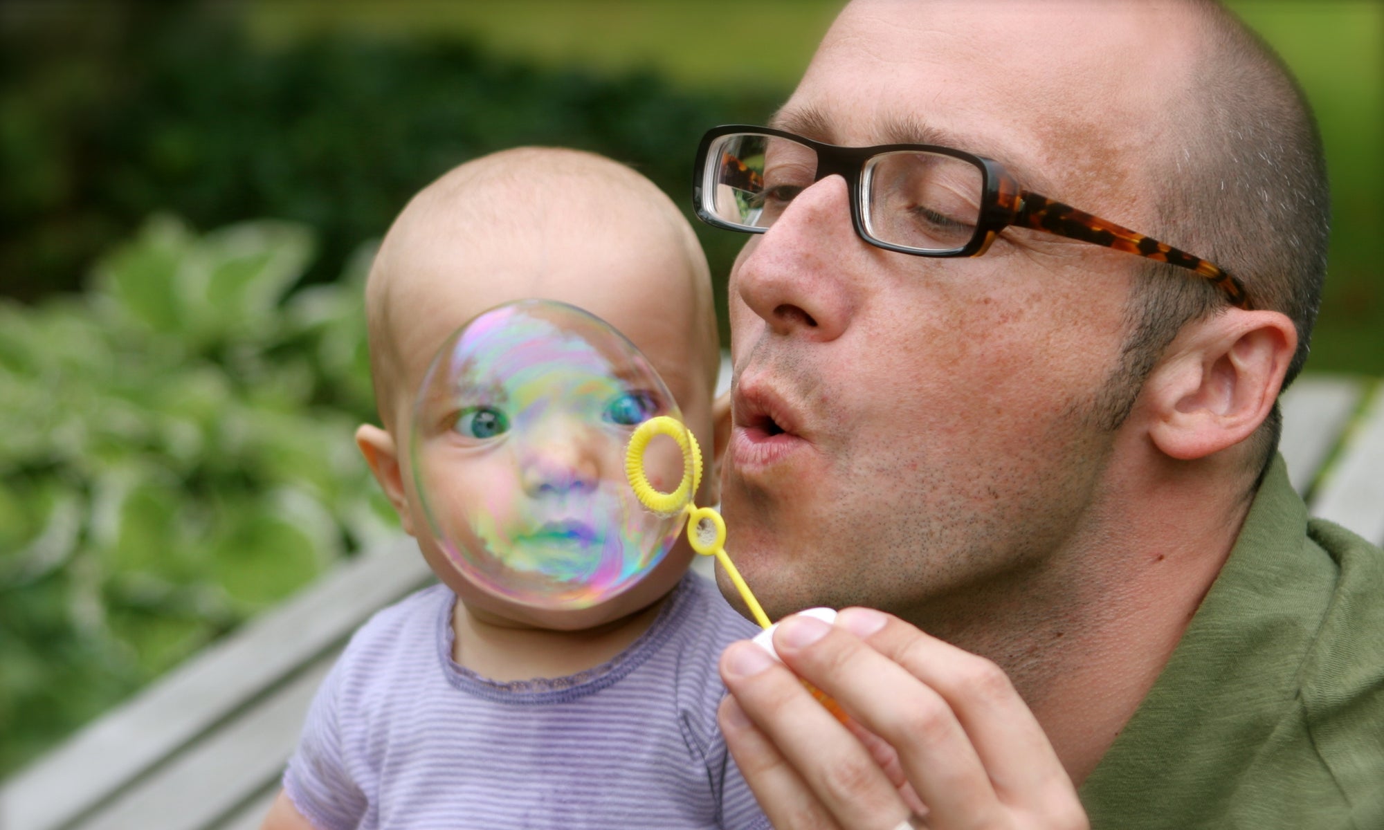 A father playing with his child, showing bubbles