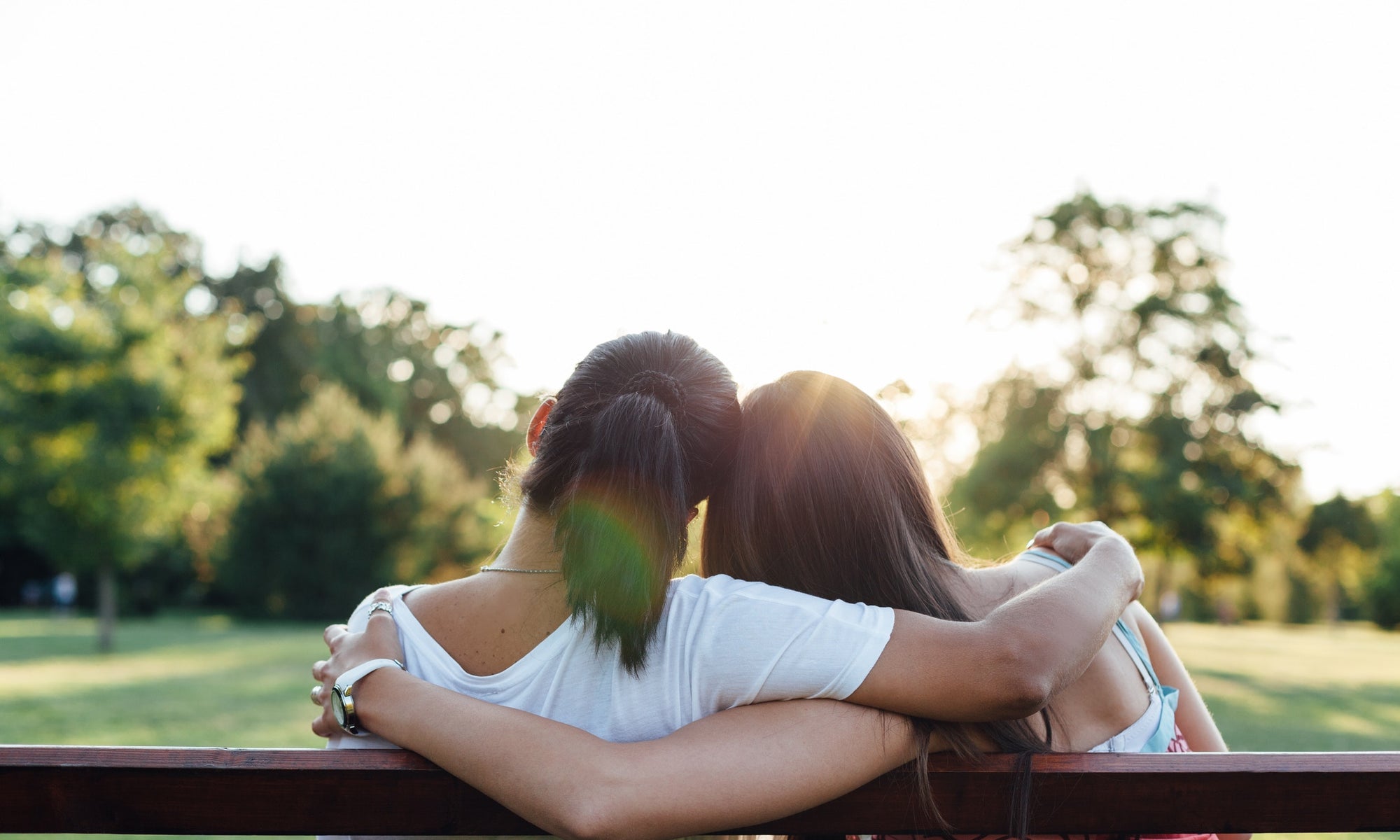 back view of two women sitting on a bench in the park