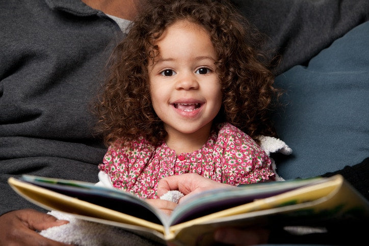 Happy curly little child girl is reading  book