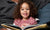 Happy curly little child girl is reading  book