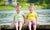 Twin girls on a lake shore, sprinkling water