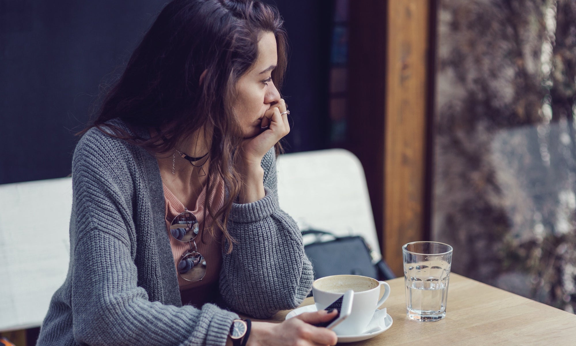 Woman sitting in a restaurant holding her mobile phone looking away