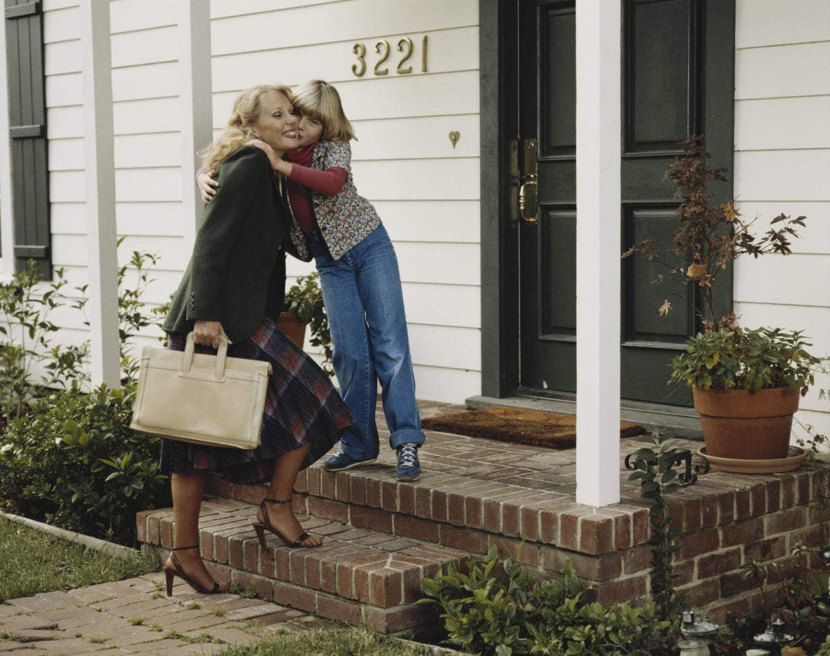 a child hugging mother outside of a house