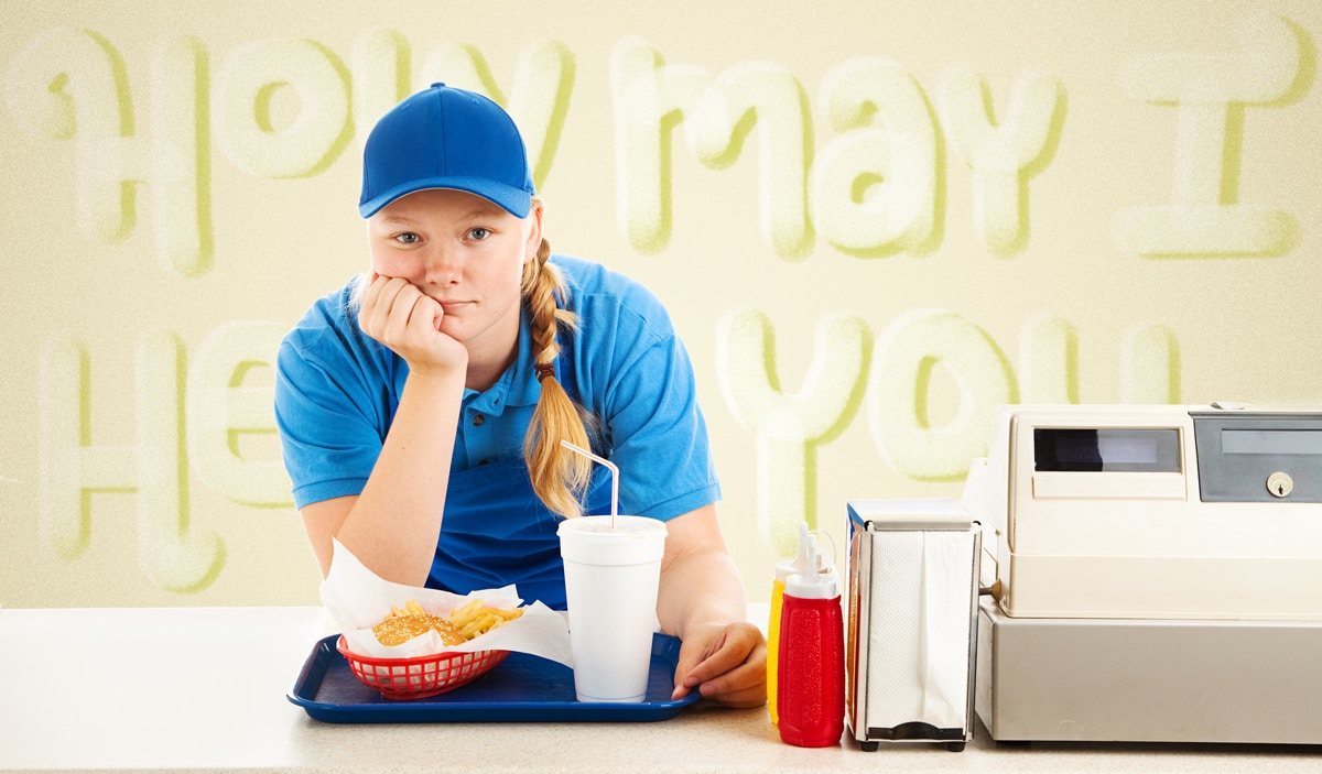 young female employee of a fast food counter standing next to cash counter