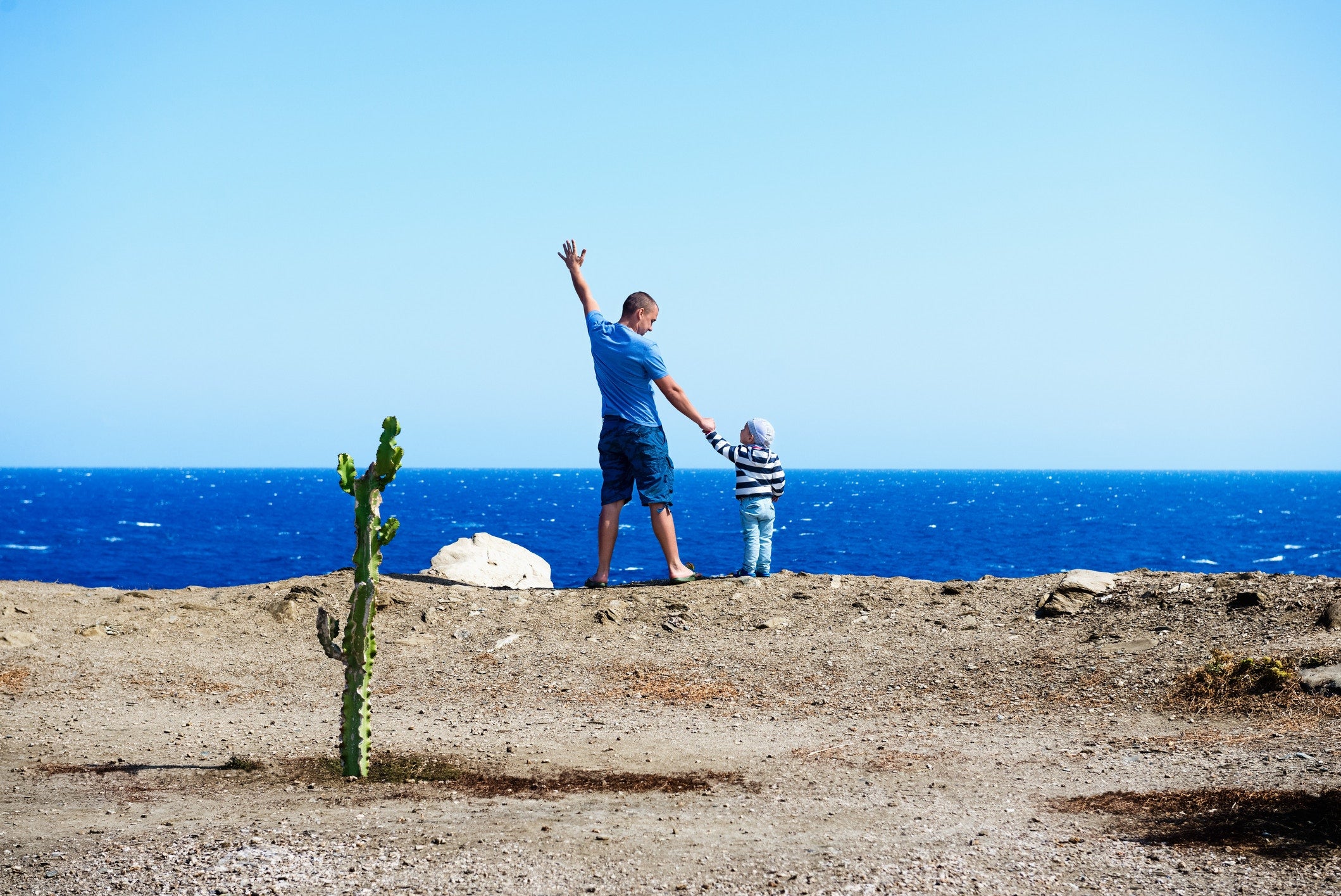 young man and a boy facing  the ocean