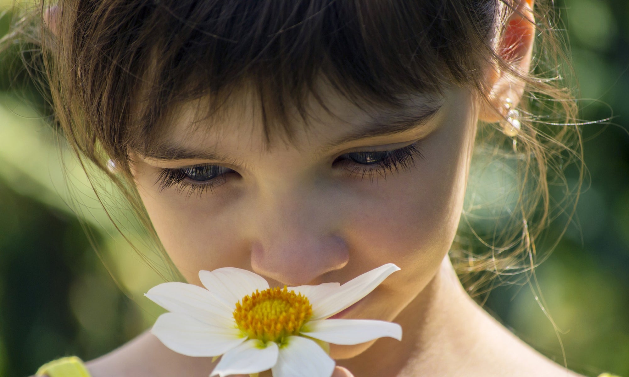 A little girl smelling flowers in a garden