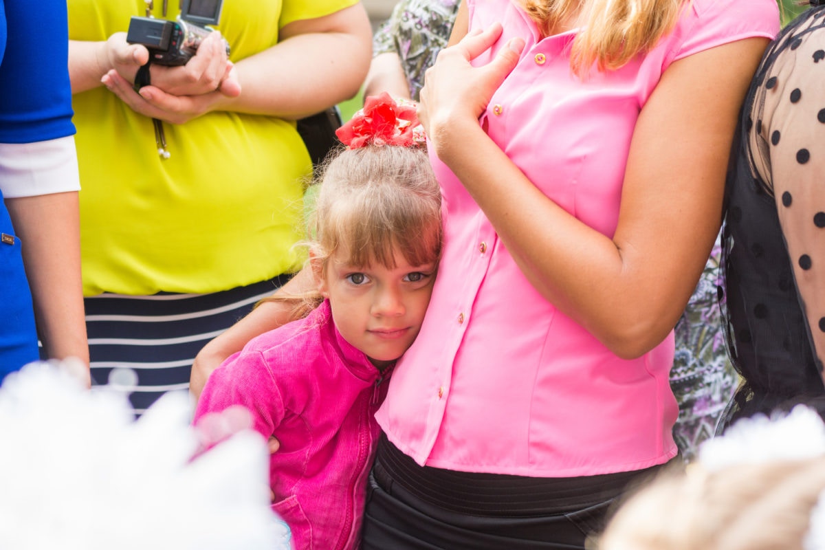 little girl standing in the crowd and clung to her mothe