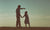 Father and daughter holding hands standing on a hill with nature lanscape back view.