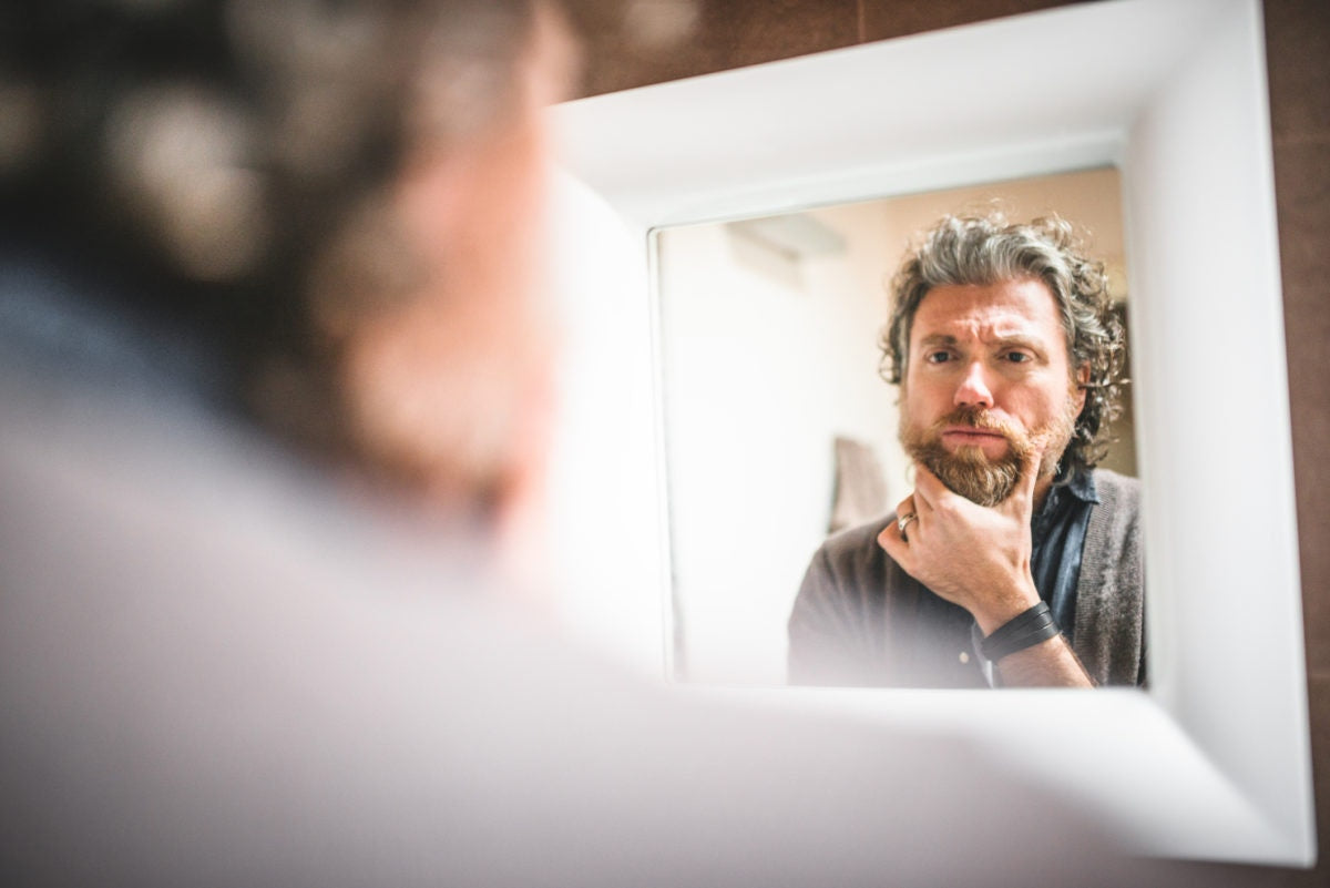 A Person seeing his image expression in mirror in an emotional way