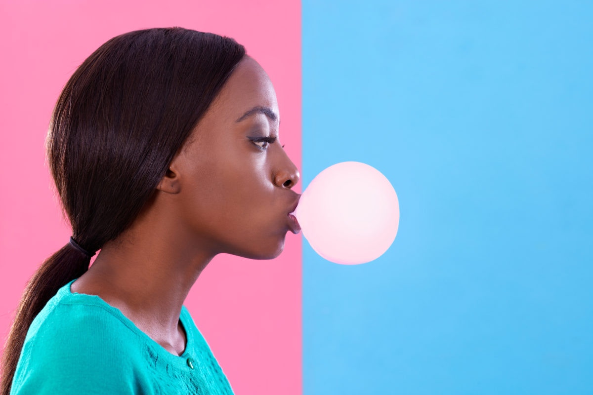 A girl is creating bubble using chewing gum