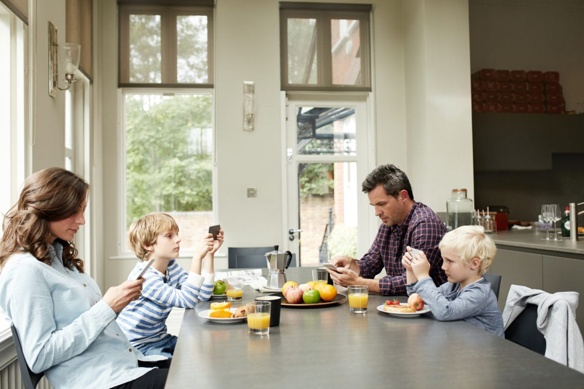 Family looking at their smartphones at the dinner table