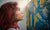 lady with red hair standing and staring at the painting on the wall