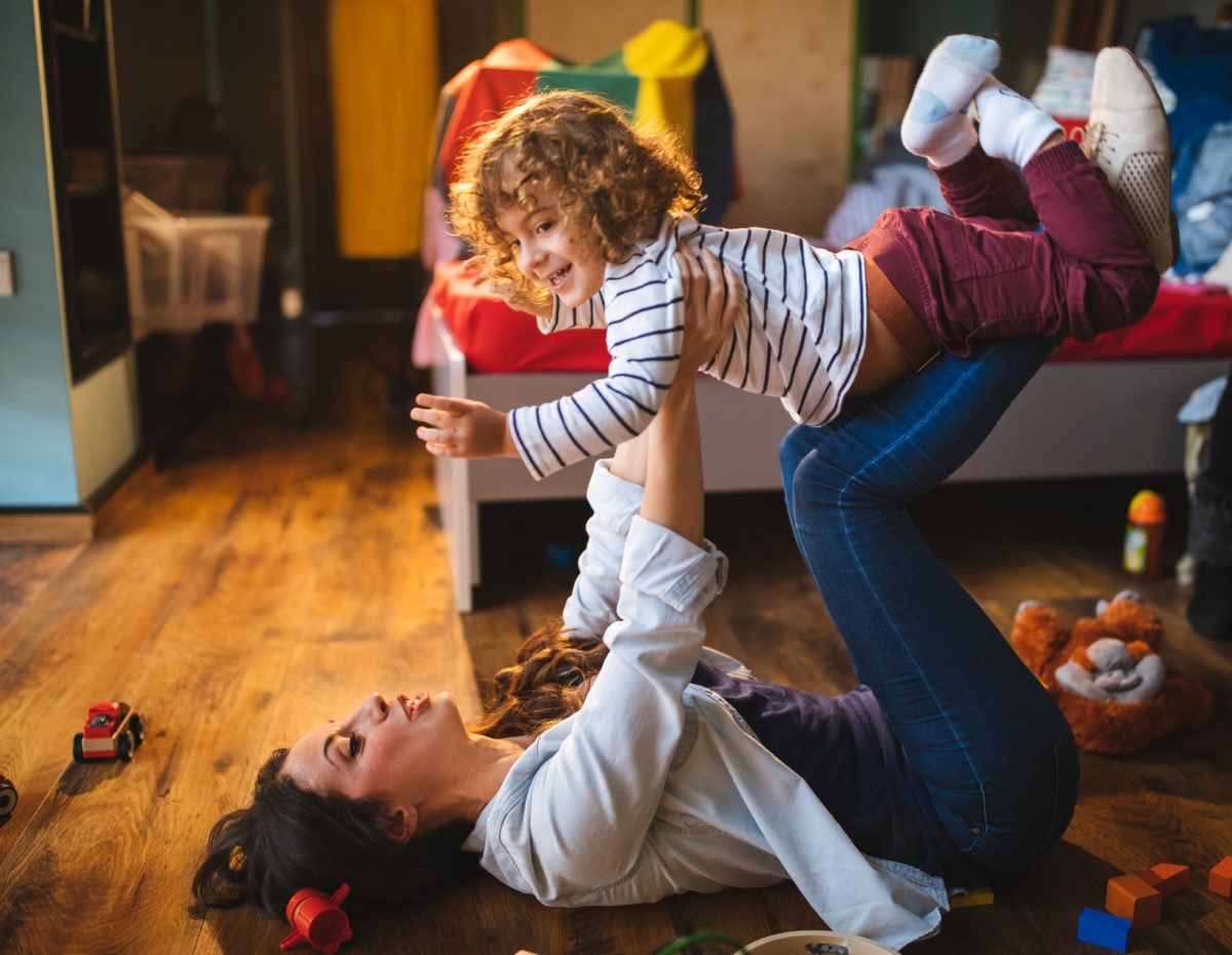 A mother is enjoying with her kid by lifting on her kegs