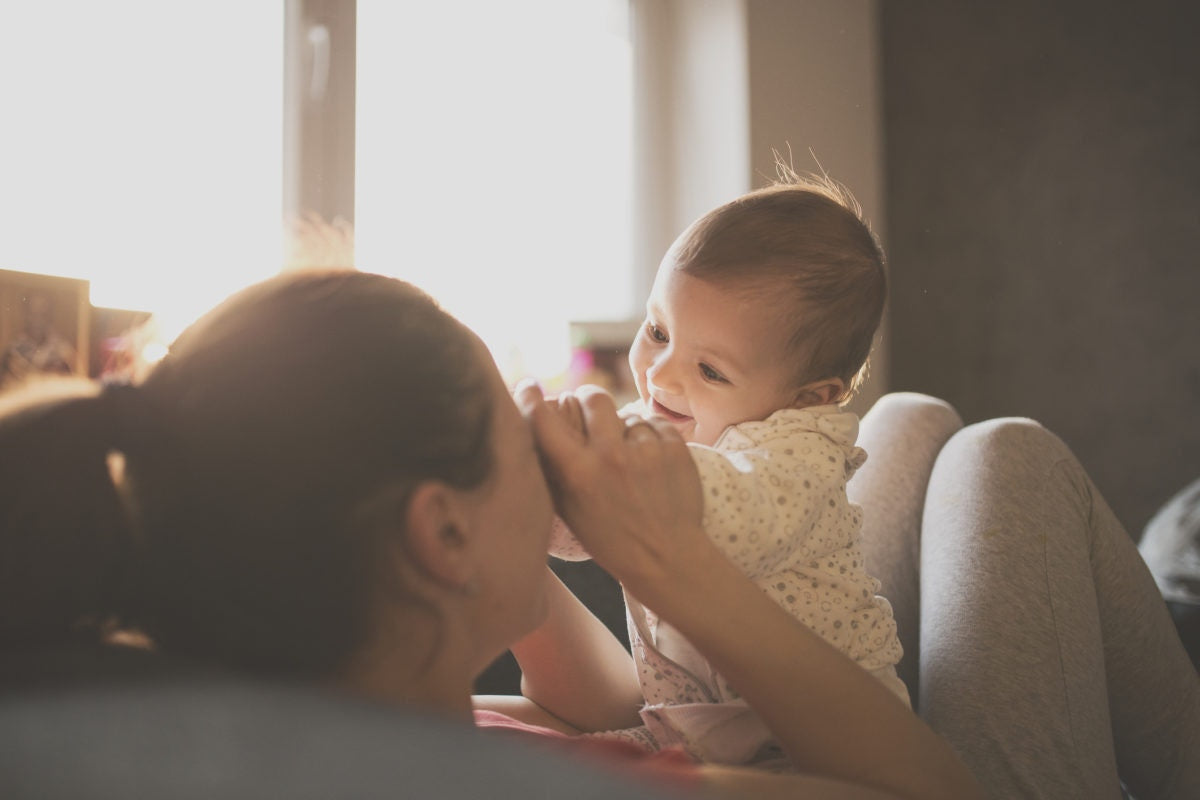 A mother is playing with her kid by closing her eyes