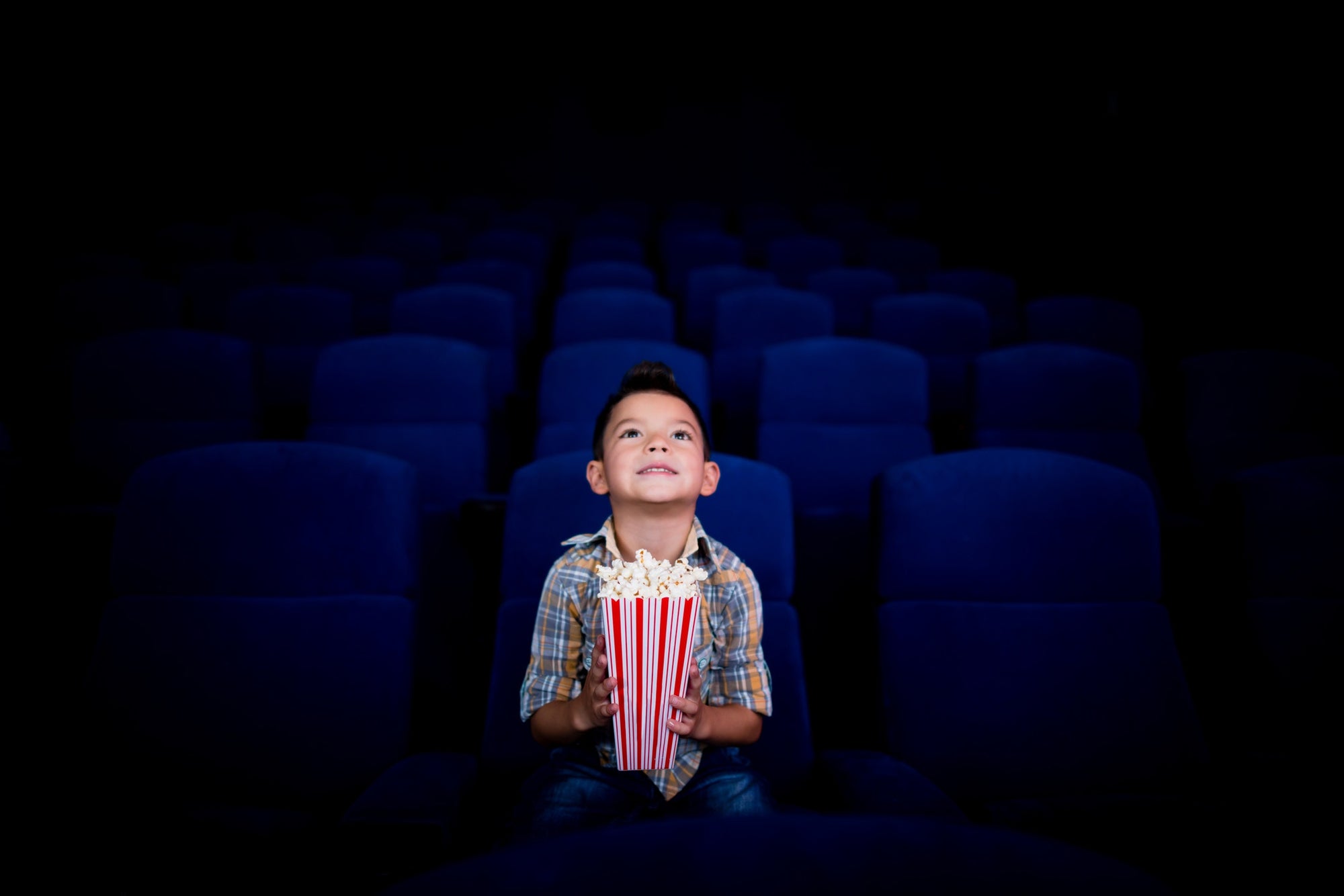 Boy sitting on a film theatre with some pop corn