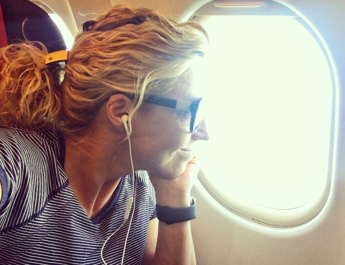 Woman is sitting and listening to music and watching outside near window in a aeroplane