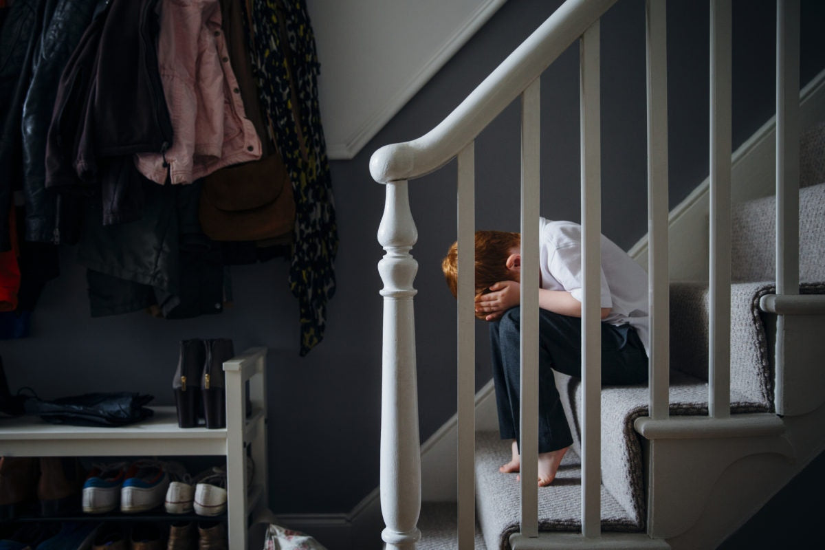 Depressed boy sitting with his head down on stairs