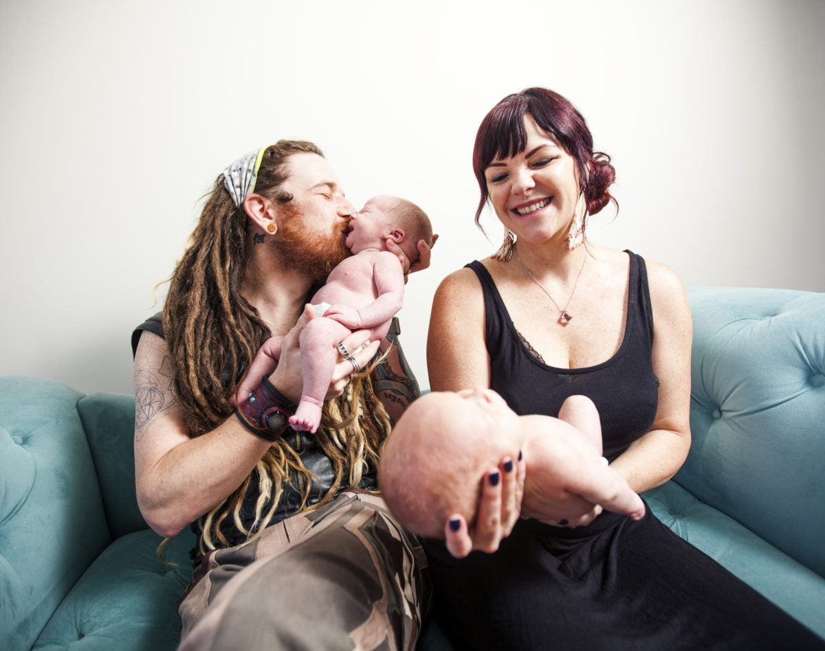 parents sitting in sofa holding twins in arms