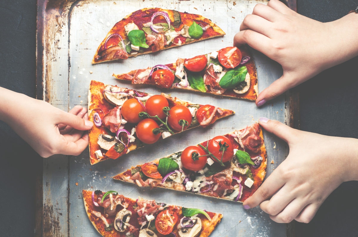 ladies holding pieces of pizza