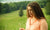 woman with curly hair in a orange hoodie against nature background