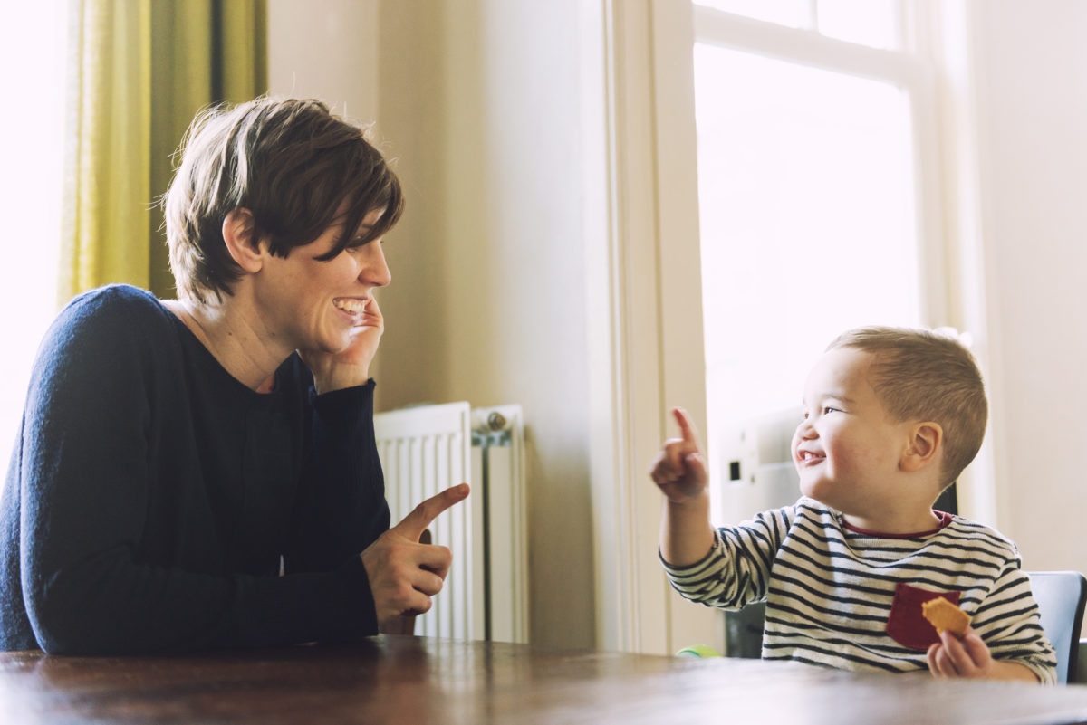 Happy mother having fun with her small boy at dining table