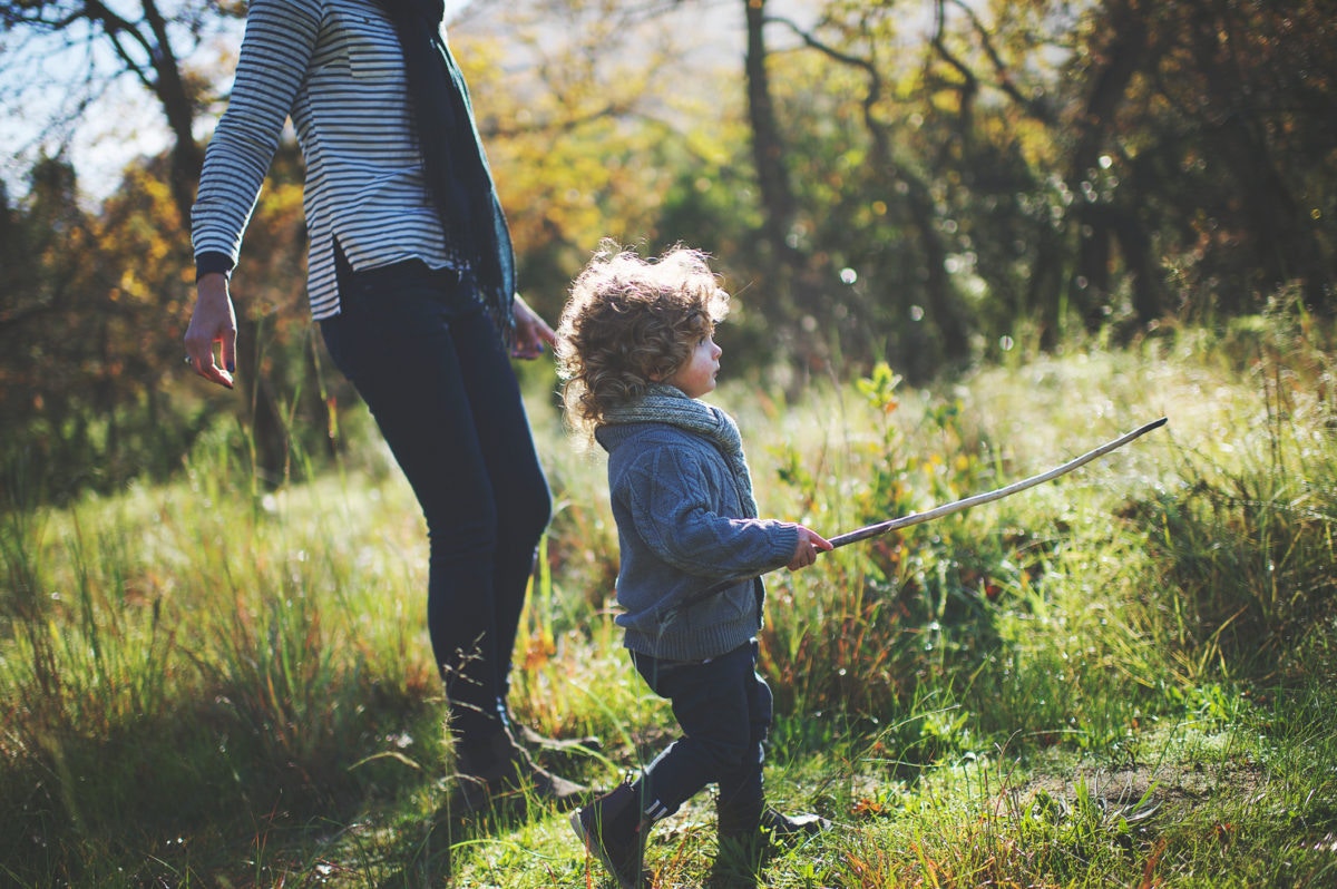 Boy holding a stick and walking with mother