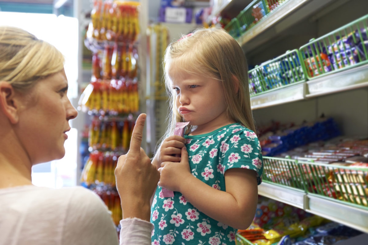 mother scolding young girl in grocery shop