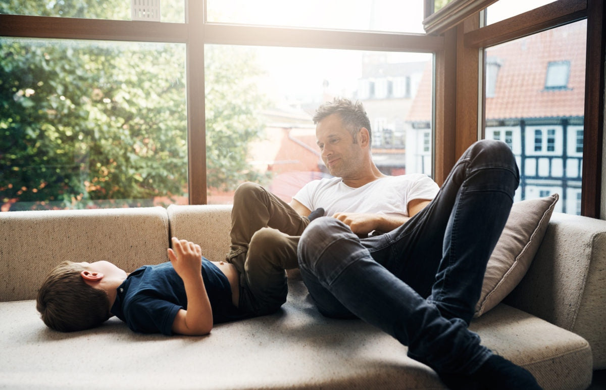 Father and child lying on a couch near the window