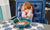 Little girl with annoyed expression sitting at a table with ears covered by her hands 