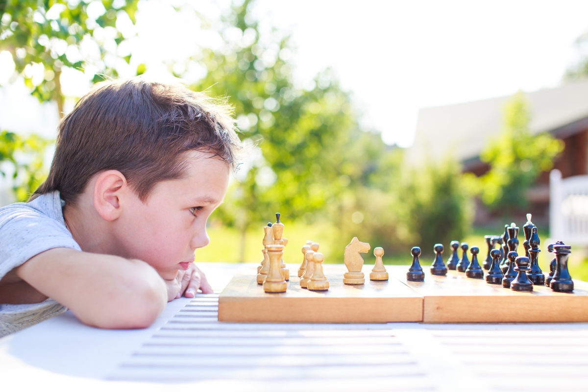 Young boy playing chess, staring at pieces on board,close-up