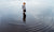 boy standing in a lake surrounded by ripples