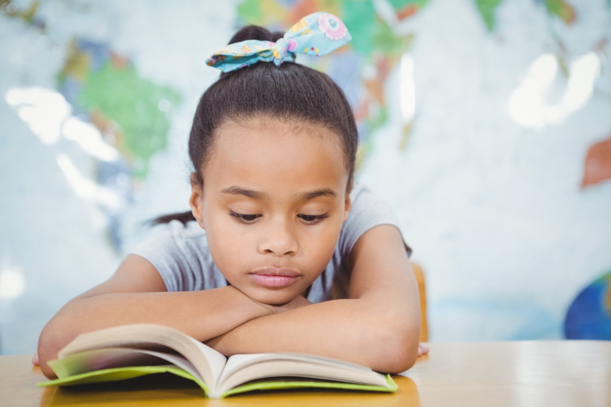 little girl reading book at the table