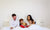 Family of four people sitting on bed in bedroom reading book