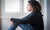 young girl sitting on floor hugging knees looking at distance