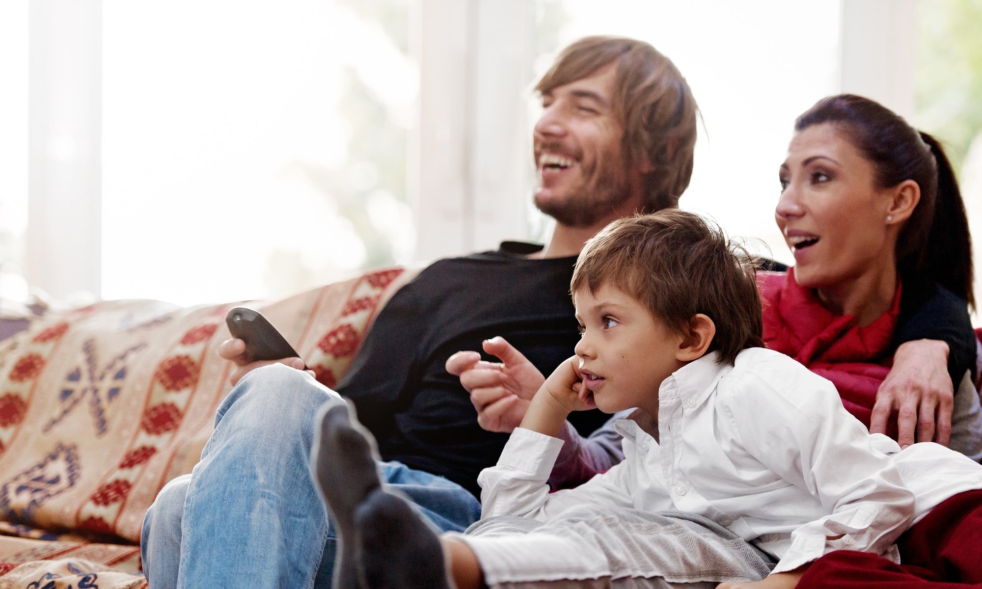 family on couch laughing while watching tv