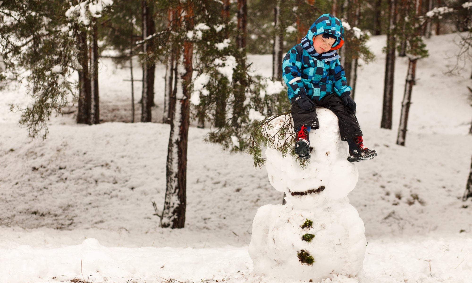 A child is sleeping on top of a ice burg with full of snow fallen