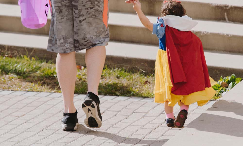 ハロウィーンの仮装をした親子が後ろから歩く姿