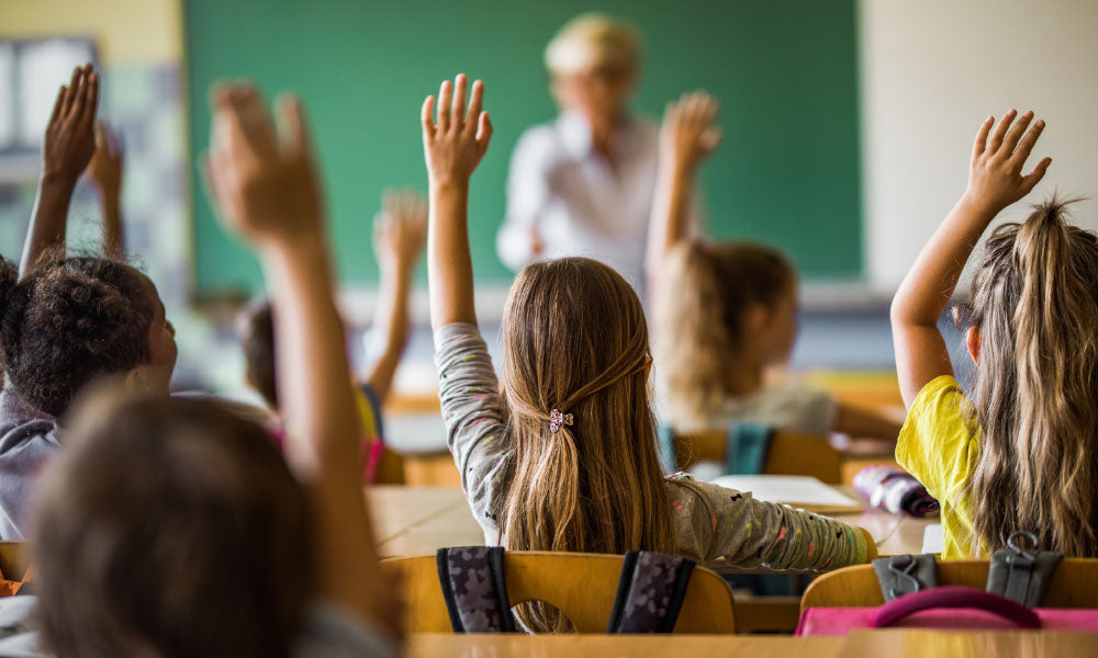 elementary students raising their arms on a class